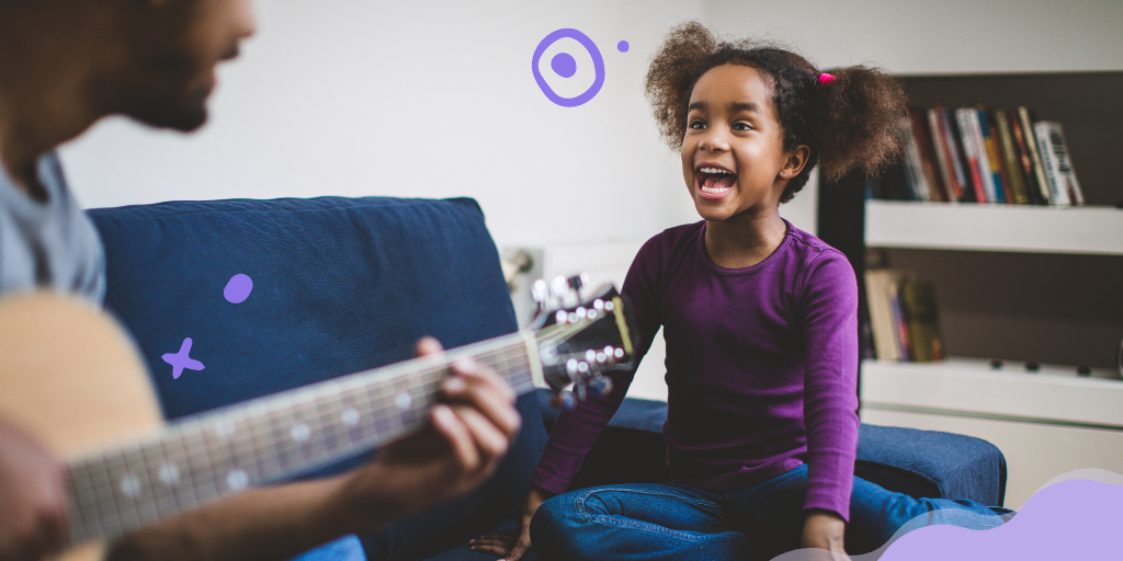 Niña sonriendo con su padre tocando la guitarra
