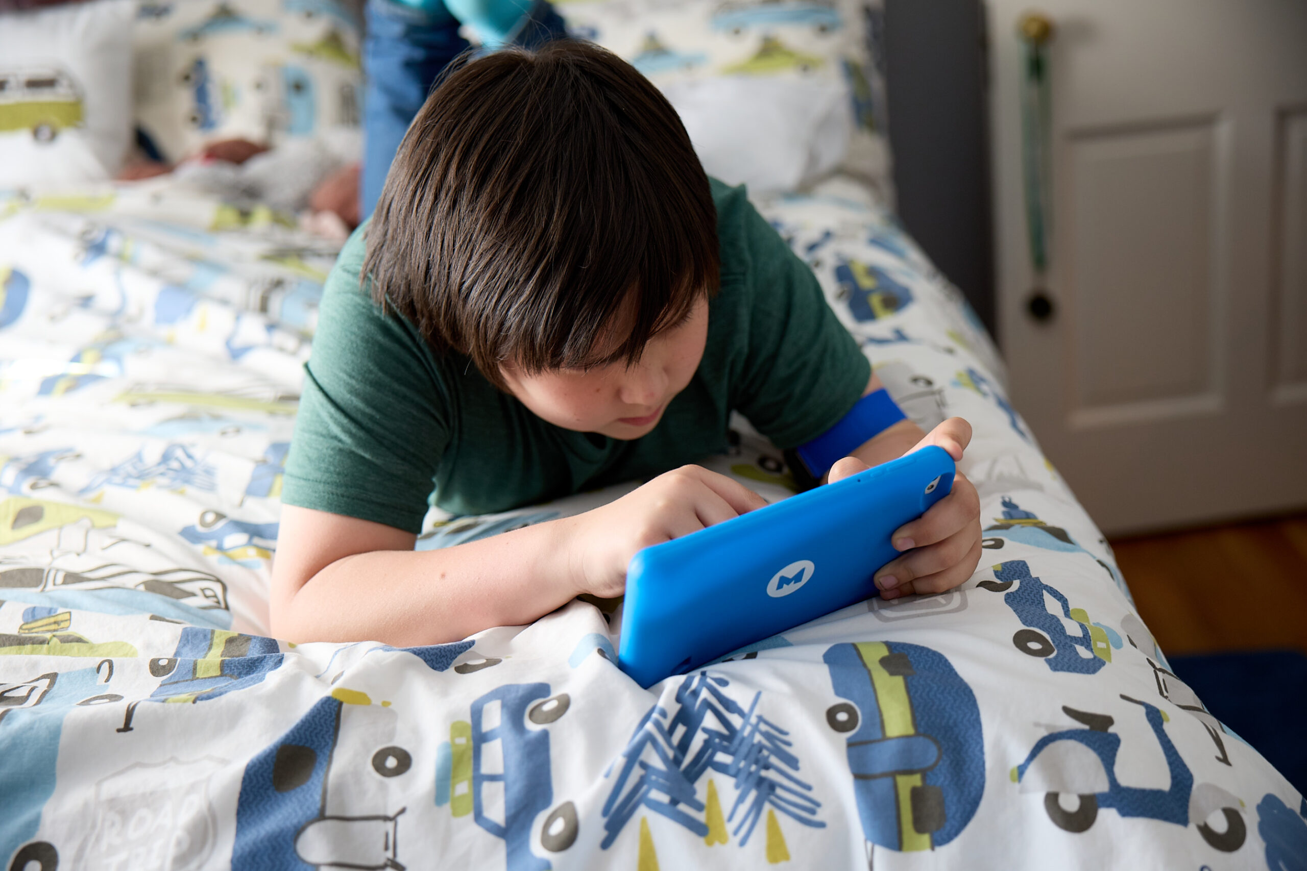 boy laying on bed playing on Mightier tablet