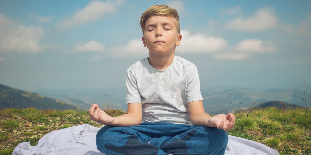 boy meditating on mountain